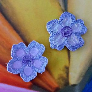 Zwei elegante Satin-Blumen zum Aufb&uuml;geln in violett mit irisierendem Schimmer aus der N&auml;he fotografiert