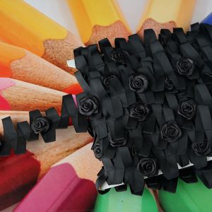 Detailansicht eines schwarzen Dekobandes in Zickzack-Form, verziert mit 3cm grossen Satinrosen auf aufgereihten Farbstiften bei Spitzentraum.ch.