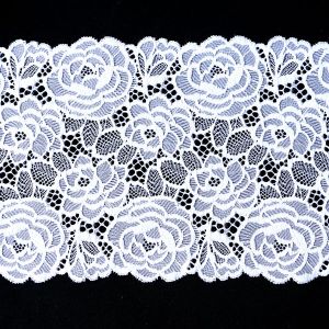 Breites elastisches Spitzenband in Weiss (19 cm) mit dichtem Rosenmuster und geschwungenen Bogenkanten auf schwarzem Grund gezeigt bei Spitzentraum.ch.