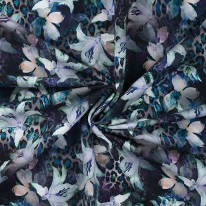Digitaldruck French Terry mit ca. 6 cm grossen, offwhite Lilien auf dunkelblauem Grund. Die t&uuml;rkisen Animalprint-Elemente im Hintergrund sind deutlich erkennbar.