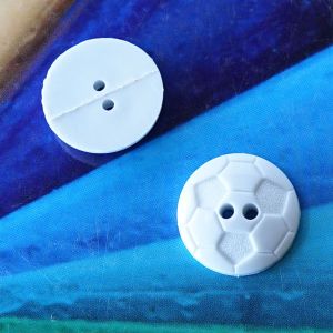 Zwei weisse Fussball-Lochkn&ouml;pfe (18mm) aus Kunststoff, einer von der Vorderseite mit Wabenmuster, einer von der glatten R&uuml;ckseite gezeigt bei Spitzentraum.ch.