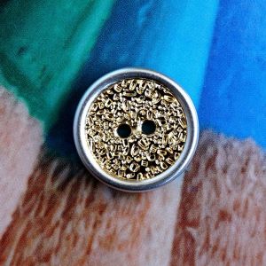 Strukturierter 20mm Kunststoffknopf in Gold mit Silberrand. Lichtbrechende Oberfl&auml;che f&uuml;r starken Glanz. Ideal f&uuml;r Kinderkleidung bei Spitzentraum.ch.