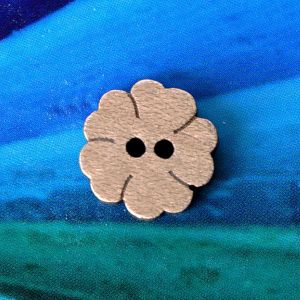 Ein einzelner, naturbelassener 14mm Kleeblatt-Holzknopf mit 2 L&ouml;chern und rustikal angekokelten Kanten vor blauem Hintergrund bei Spitzentraum.ch.