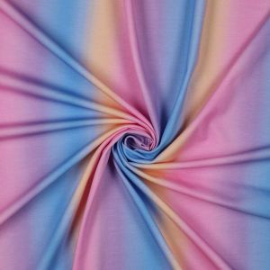 Single Jersey Stoff im Regenbogen Farbverlauf, aufgerollt. Rosa, Hellblau, Orange. Bielastische Baumwolle für Kinder- & Damenbekleidung.