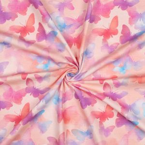 Hochwertiger Digitaldruck-Jersey in Lachs mit bunten Schmetterlingen in Pink und Lila. Detailansicht der weichen Stoffstruktur mit elegantem Faltenwurf.