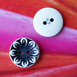Zwei schwarz-weisse Blumenkn&ouml;pfe (16mm), wovon einer die detaillierte Vorderseite mit Reliefstruktur und der andere die glatte, helle R&uuml;ckseite zeigt.