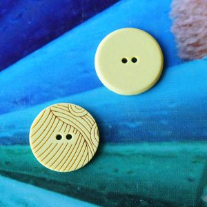 Zwei gelbe 18mm-Kunststoffkn&ouml;pfe zur Ansicht der bedruckten Vorderseite mit Linienmuster und der unifarbenen R&uuml;ckseite bei Spitzentraum.ch.