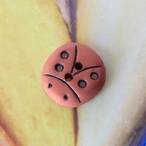 Marienk&auml;fer-Kunststoffknopf (14x15mm) in Terracotta mit eingesenkter schwarzer Pr&auml;gung von Punkten und Linien auf gelbem Grund bei Spitzentraum.ch.