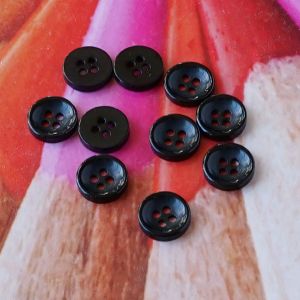 Zehn kleine, flache Kunststoffkn&ouml;pfe in Schwarz (8mm Durchmesser) mit 4 L&ouml;chern auf einem farbigen Hintergrund platziert f&uuml;r Spitzentraum.ch.