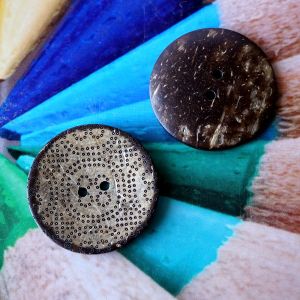 Zwei 39mm grosse Kokoskn&ouml;pfe aus naturbelassener Schale zur Ansicht der hellen Vorderseite mit gepr&auml;gtem Punktmuster und der dunklen R&uuml;ckseite bei Spitzentraum.ch.