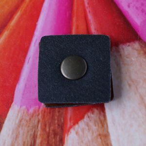 R&uuml;ckseite bzw. geschlossene Ansicht des quadratischen, braunen Lederpatches mit der runden Altmessing-Kappe des Druckknopfes bei Spitzentraum.ch.