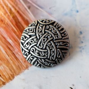Runder 13mm Ösenknopf aus Kunststoff in Altsilber-Optik. Reliefartiges Muster mit verschlungenen Ornamenten im Kelten-Stil für Jacken und Mäntel.