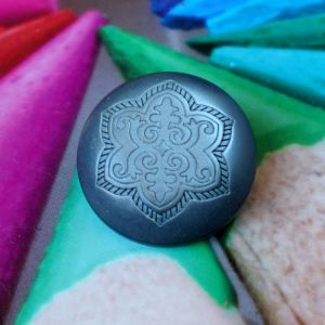 Nahaufnahme des halbrunden &Ouml;senknopfs (28mm) mit silbergrau schimmerndem Ornament-Motiv.