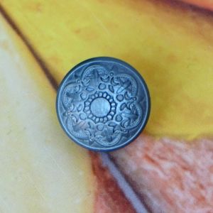 Halbrunder &Ouml;senknopf in Grau (18 mm) mit filigranem, silbergrau schimmerndem Rosetten-Ornament.