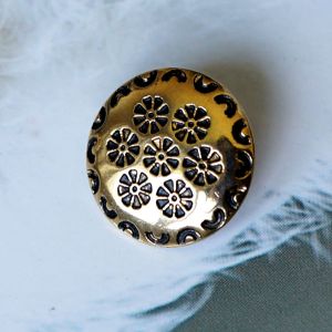 Nahaufnahme eines runden Messingknopfs (15mm) mit floraler Pr&auml;gung und dunkler Patina. Rustikaler Metallknopf ideal f&uuml;r Trachten und Strickmode.