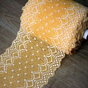 Breites elastisches Spitzenband in Orange (22 cm) mit hellecrū-farbenem Bogenmuster und feinen Bogenkanten auf Holzgrund gezeigt bei Spitzentraum.ch.