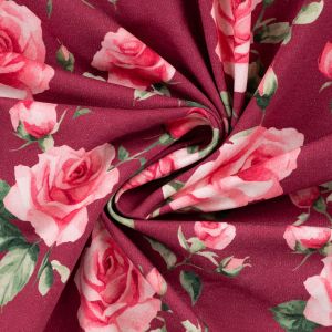 Weich fallender elastischer Sweatstoff in Dunkelrot mit romantischem Rosenmuster im eleganten Faltenwurf gezeigt auf Spitzentraum.ch.
