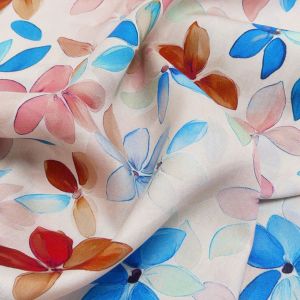 Nahaufnahme von drapierter Viskose mit buntem Blumenmuster in Blau, Rosa und Türkis auf hellem Untergrund.